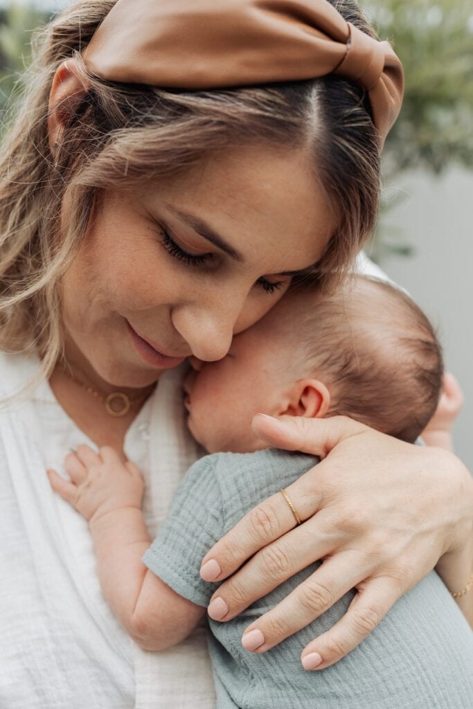 Eine Frau hält ein Baby und trägt dabei ein Stirnband.
