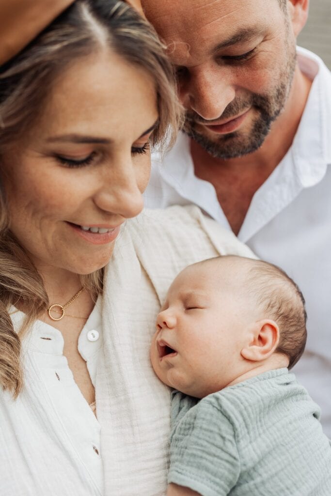 Ein Mann und eine Frau halten ein Baby im Arm.