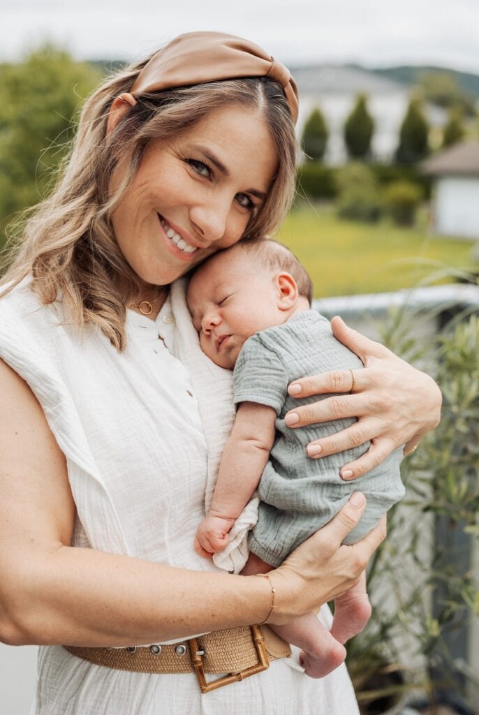 Eine Frau hält ein Baby auf einem Balkon.