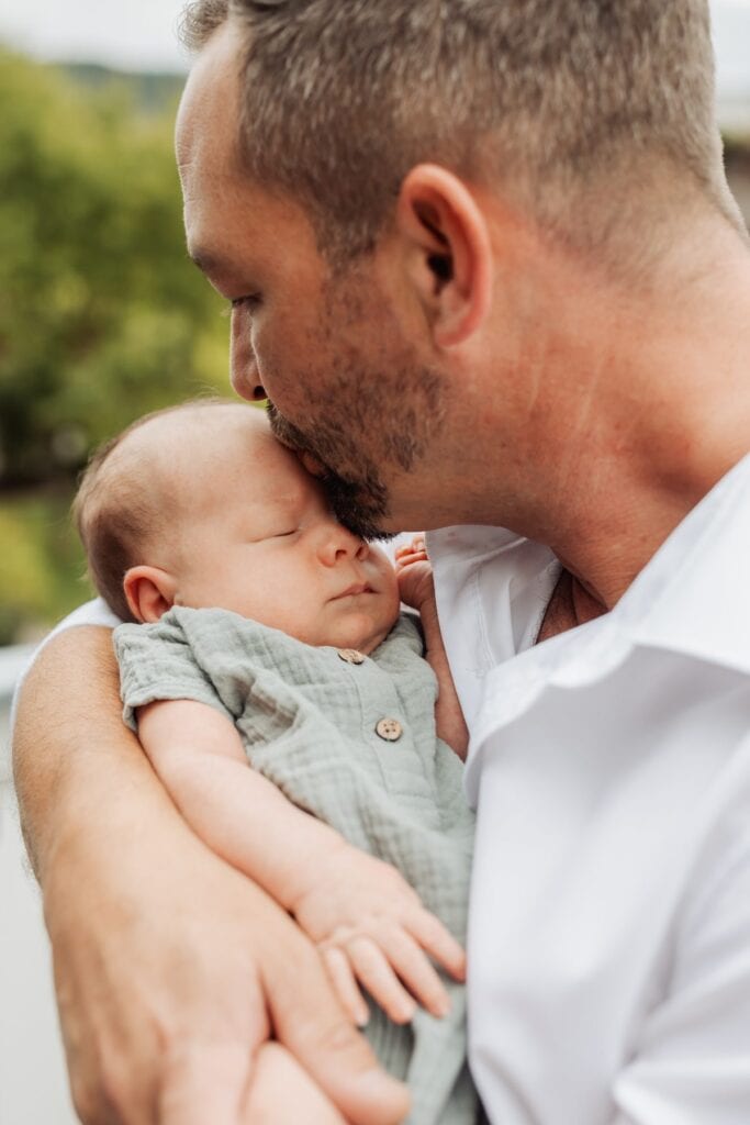 Ein Mann küsst sein Baby, während er ein Baby in seinen Armen hält.
