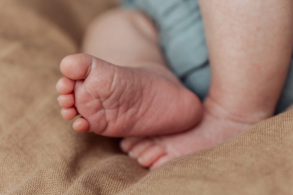 Eine Nahaufnahme der Füße eines Babys auf einem Bett.