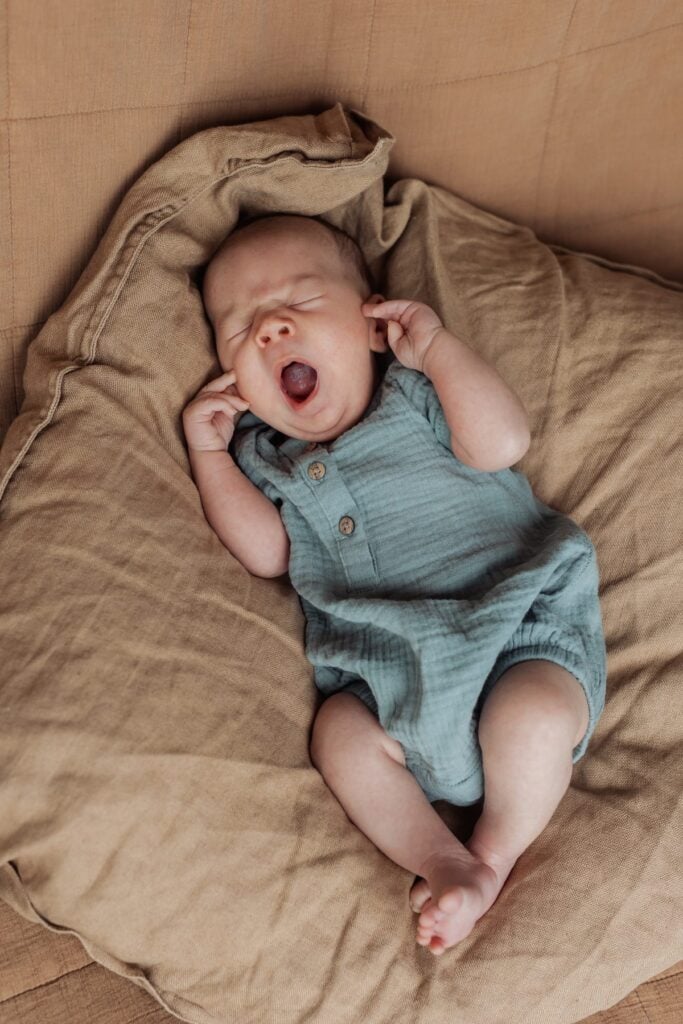 Ein Baby schläft auf einem Kissen auf einer Couch.