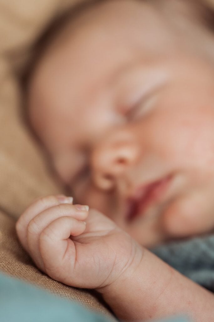 Eine Nahaufnahme eines Babys, das auf einer Decke schläft.