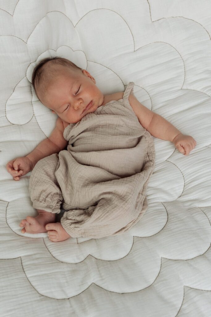 Ein Baby schläft auf einer weißen Steppdecke.