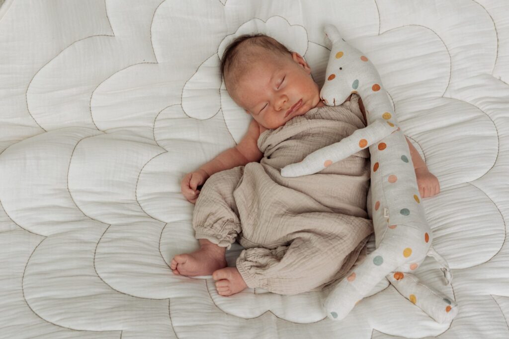 Ein Baby schläft auf einer Decke mit einem Stofftier.