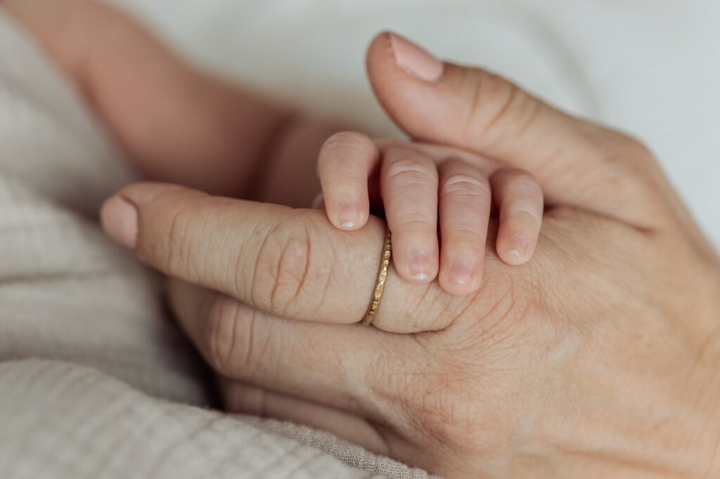 Die Hand einer Frau hält den Ring eines Babys.