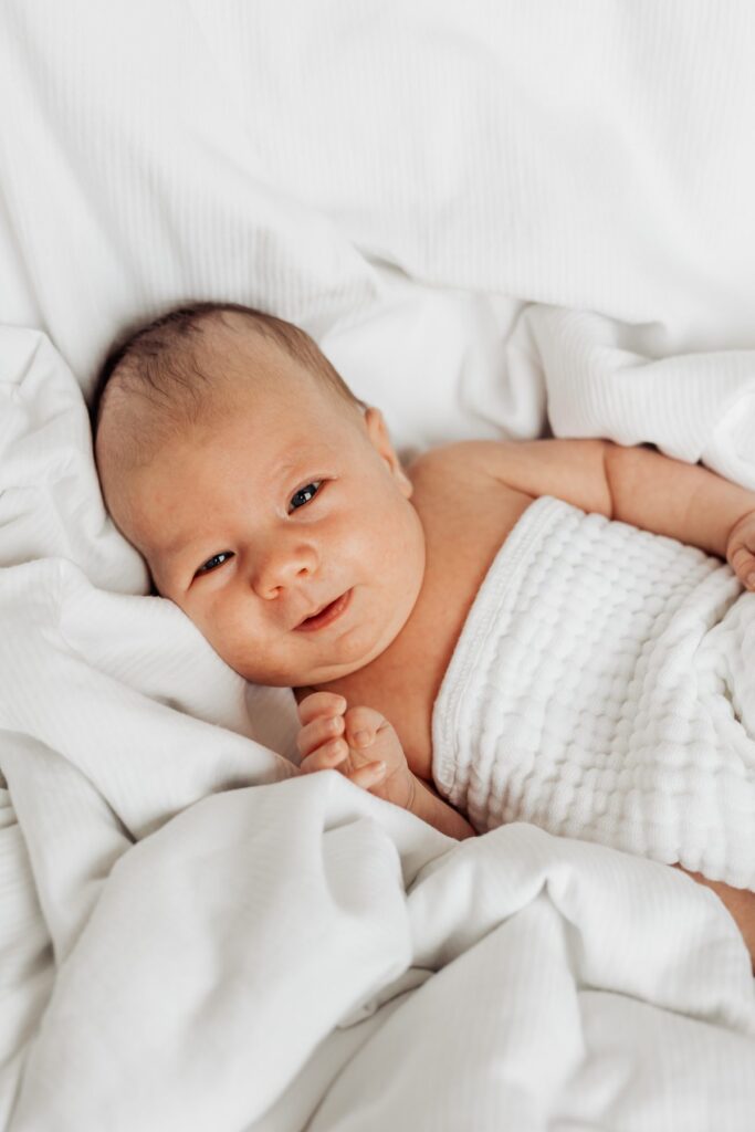 Ein Baby liegt auf einer weißen Decke.