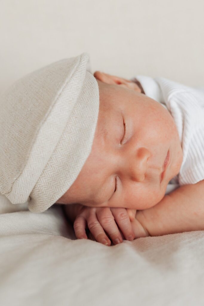 Ein Baby schläft auf einem Bett mit einer Mütze auf dem Kopf.