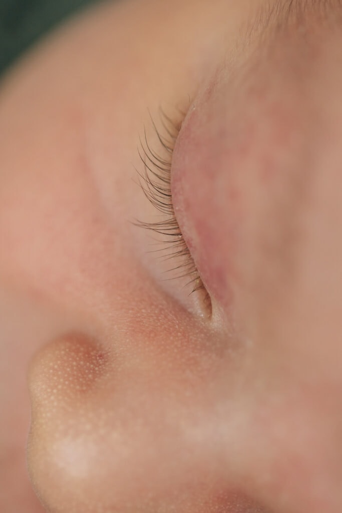 Nahaufnahme des geschlossenen Auges und der Nase einer Person. Die zarten Wimpern und die Hautstruktur sind zu sehen.